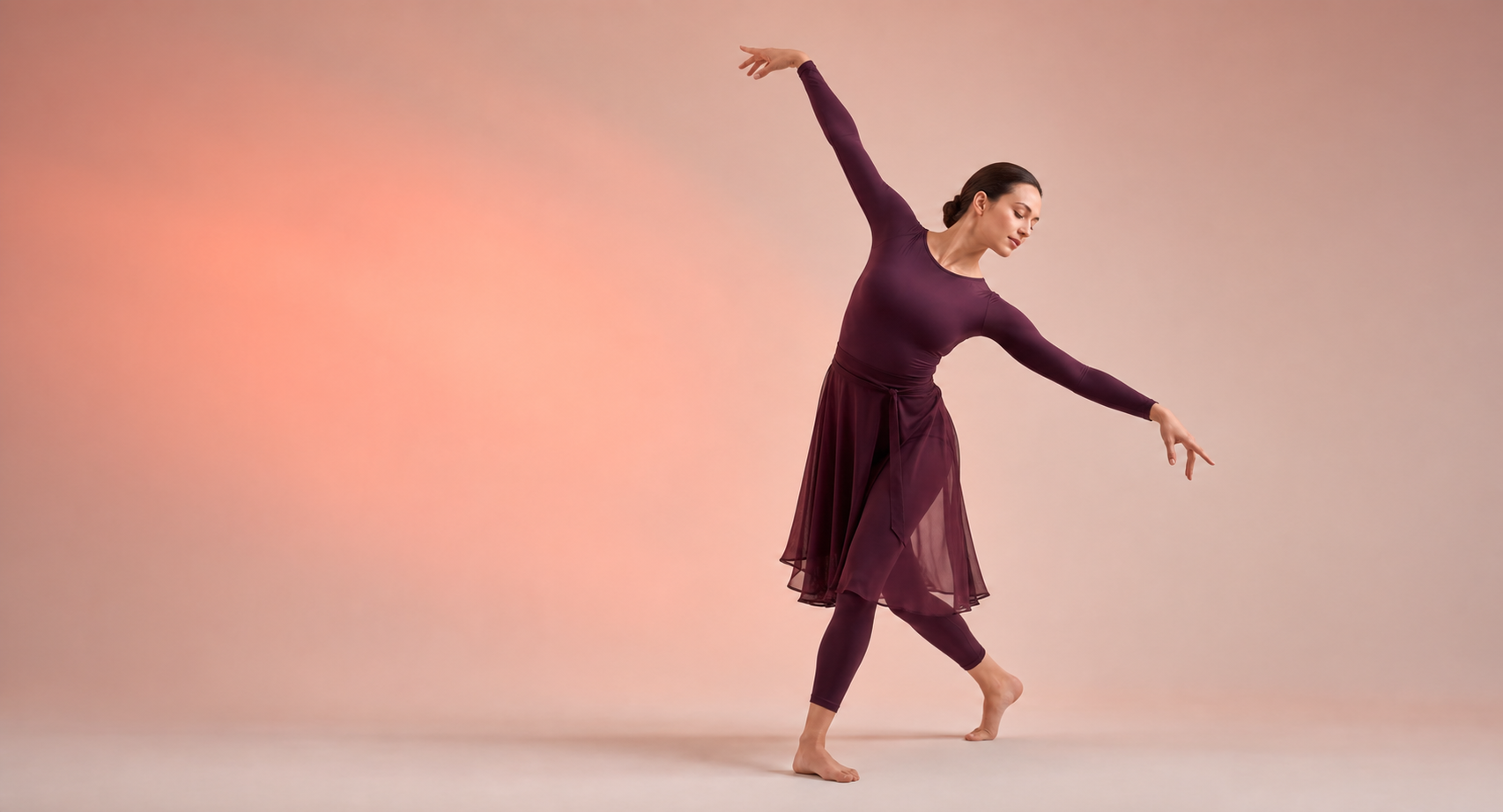 Professional dancer in graceful motion on a soft blush studio background